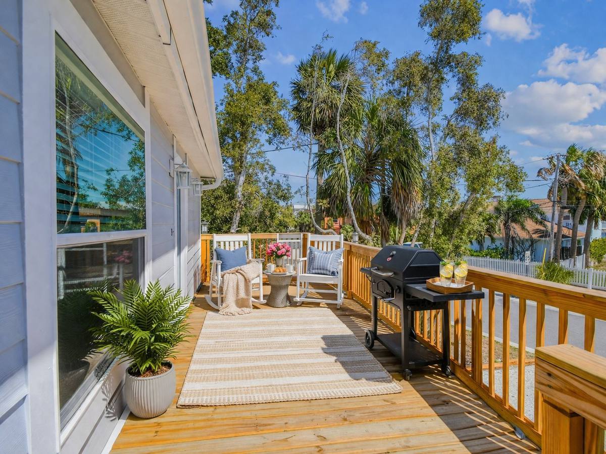 Sunny deck with grill, palms and rocking chairs at Indian Rocks Beach 2-bedroom rental
