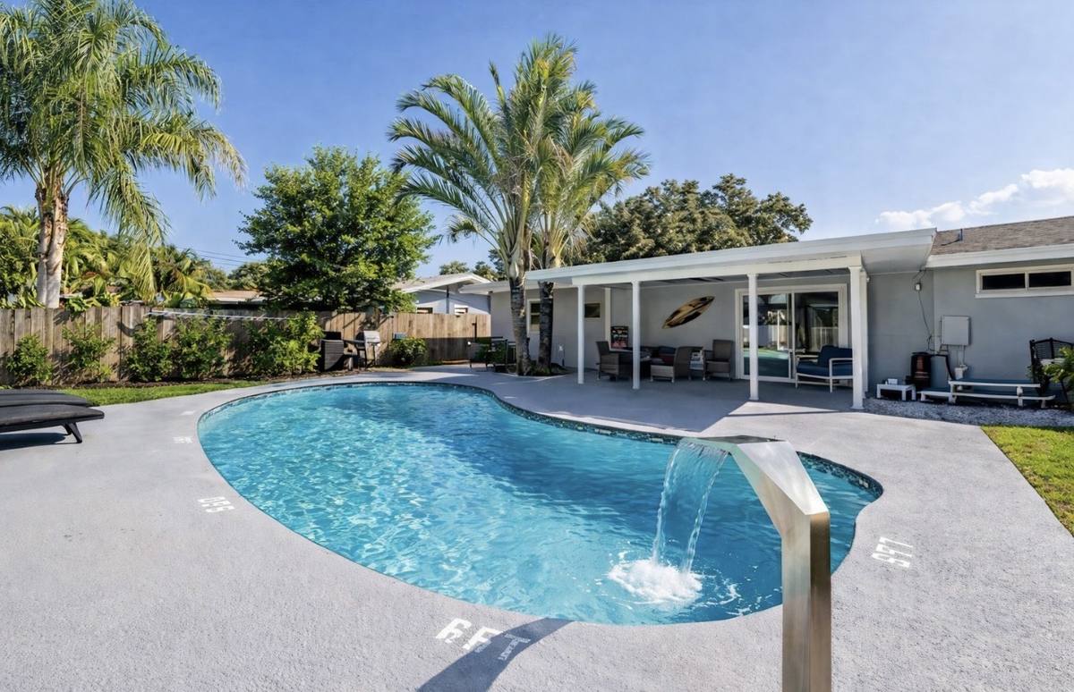 Heated pool with cascading waterfall in resort-style backyard at Largo vacation home