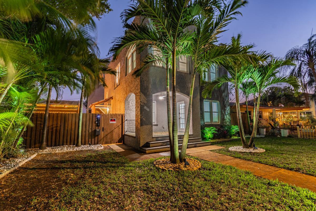 Backlit palm exterior of St. Pete bungalow at twilight with bold lighting