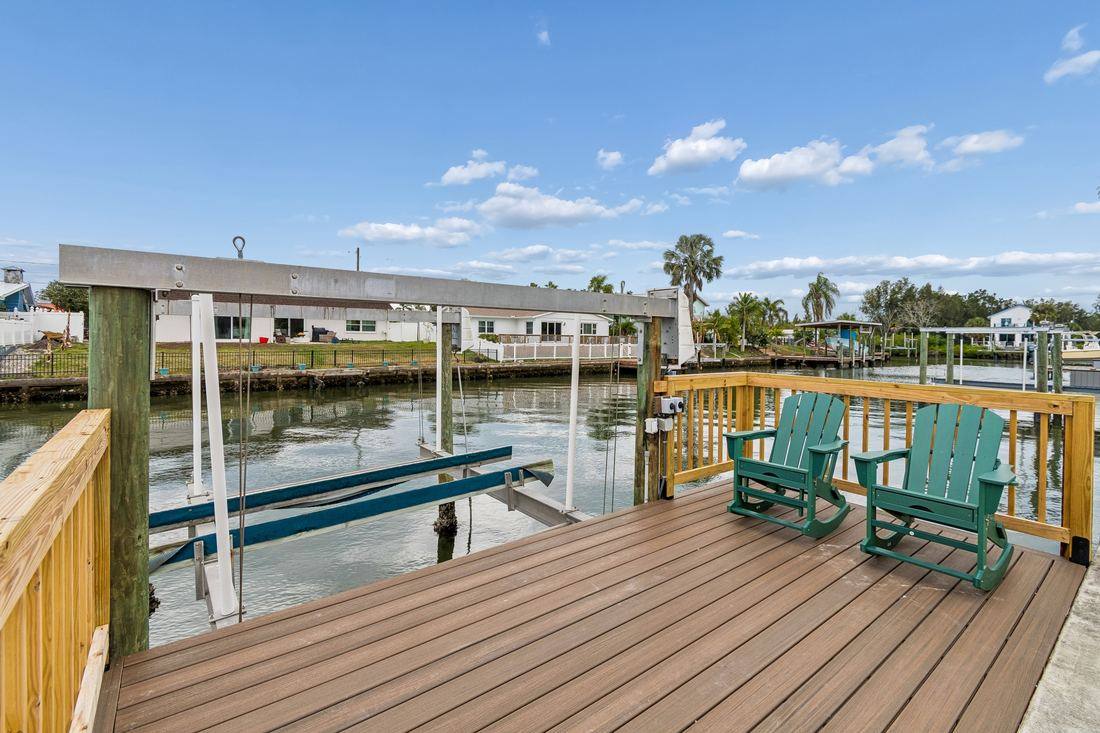 Private dock with green Adirondack rocking chairs and boat lift on Tampa Bay canal