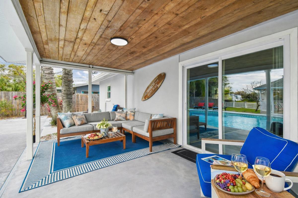 Covered outdoor living room with sectional, dining and pool view at Largo home