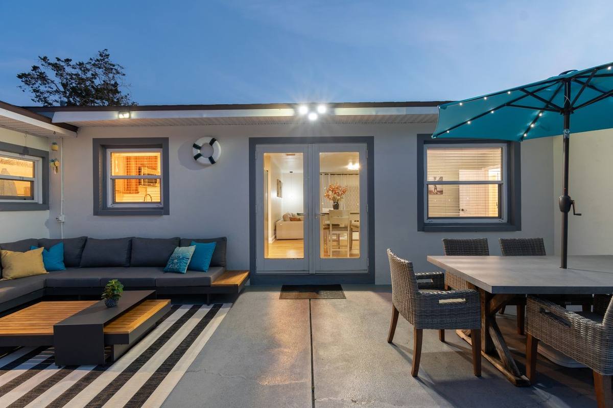 Stone fire pit with teal Adirondack chairs in fenced backyard at Clearwater rental